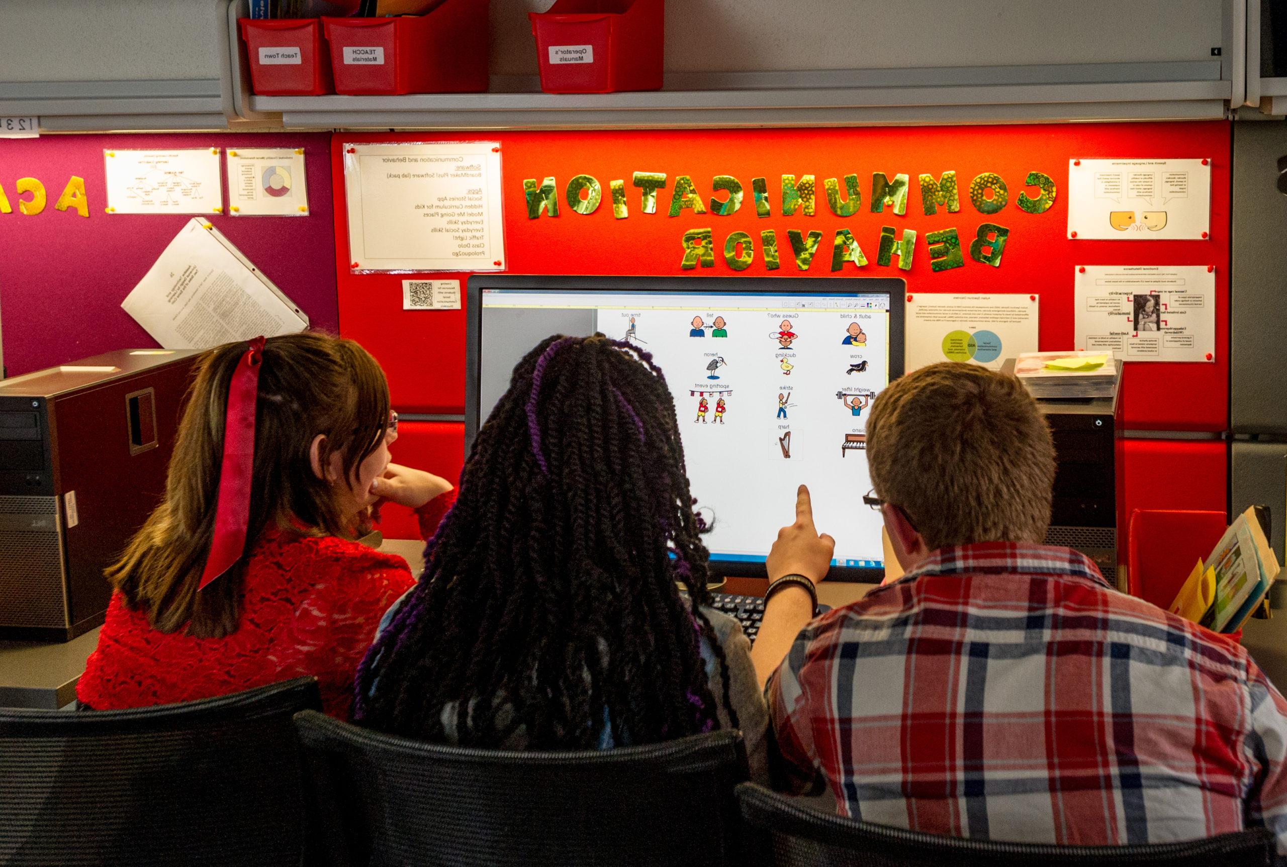 Three students working on a computer together.