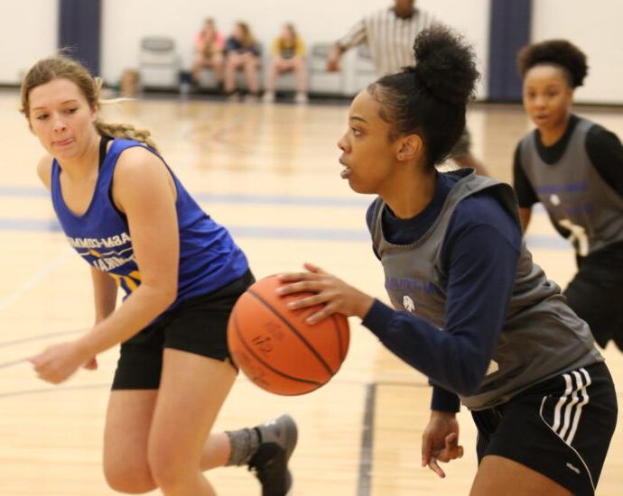 Three females students playing basketball.