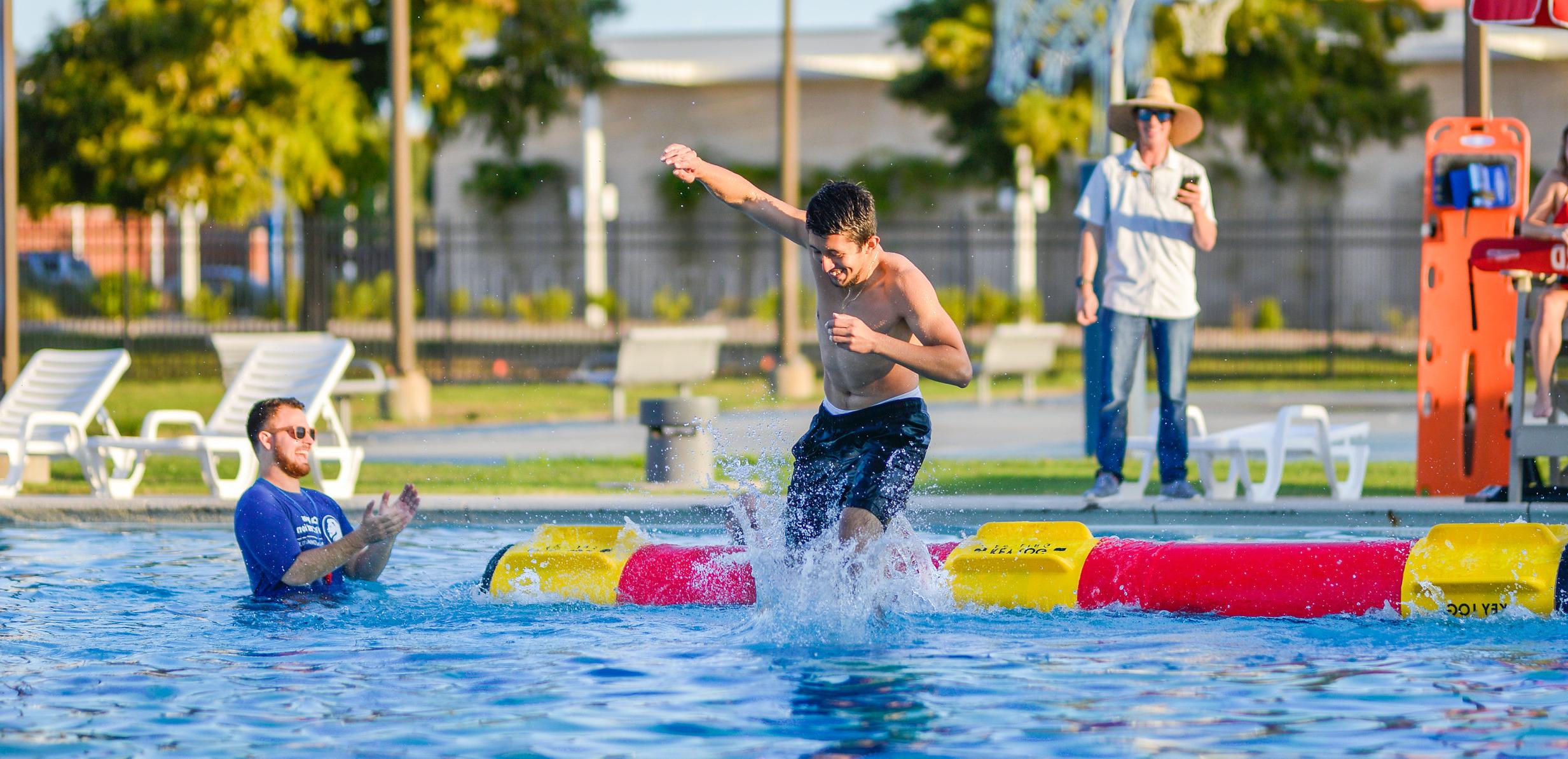 A student during a log rolling competition at the 校园娱乐 pool. 