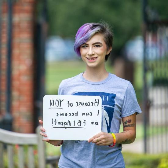 A student with a sign appropriating her opportunity.