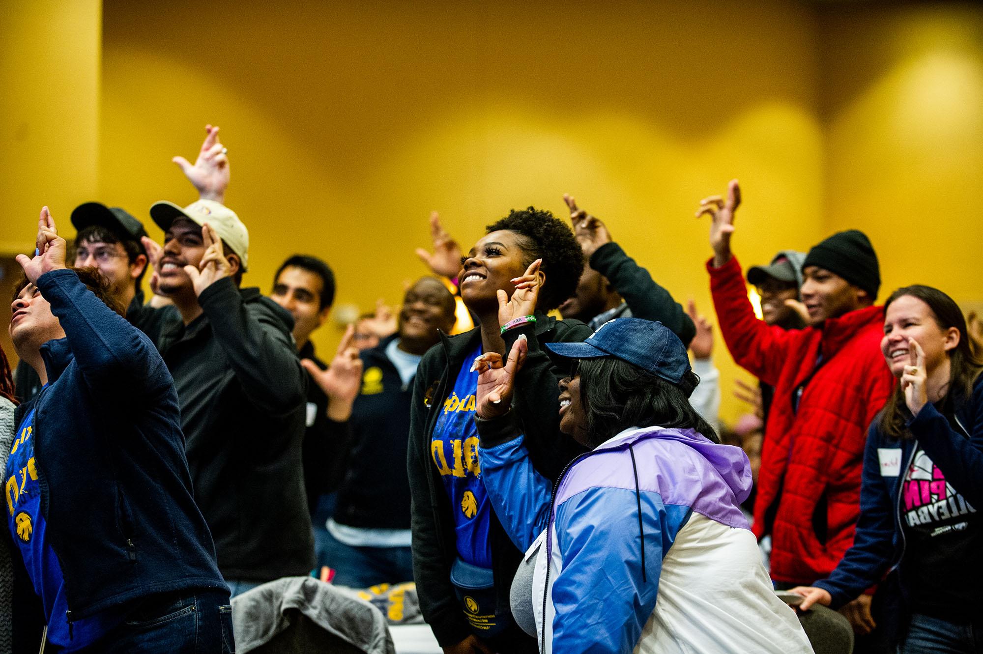 A group of students signing the leo sign in an event.