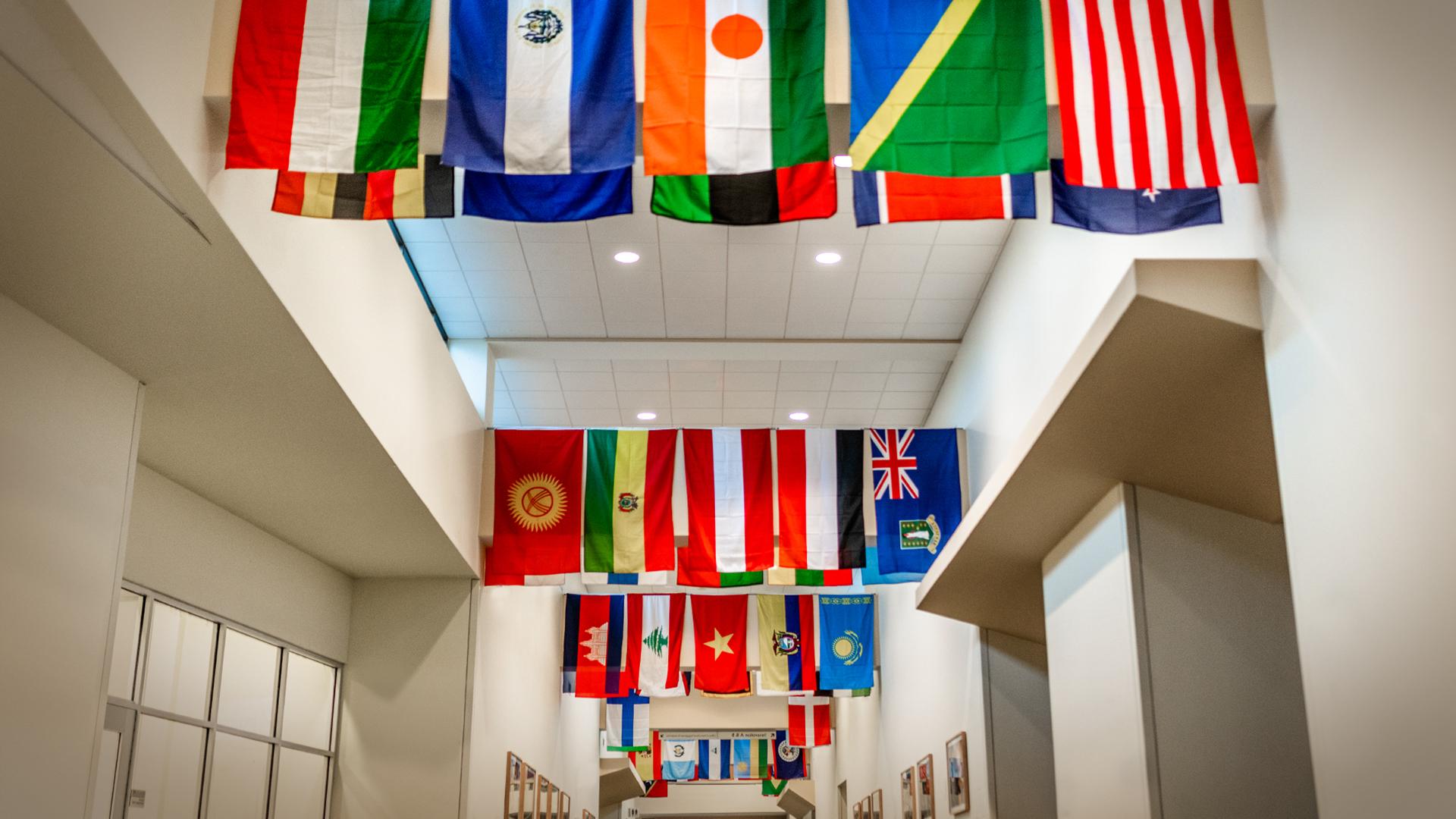 Inside of building with international flags on the ceiling.