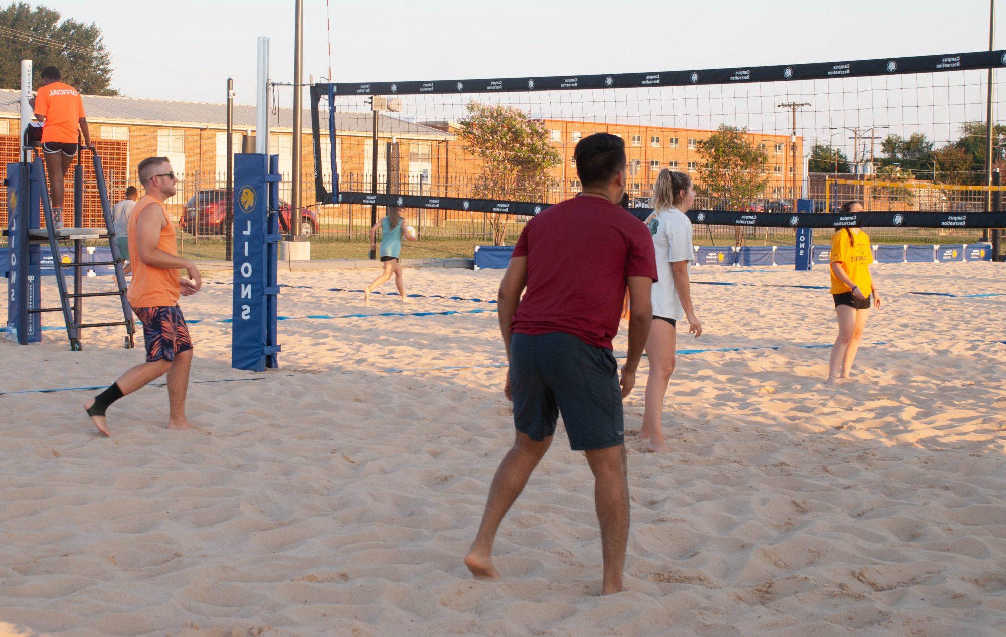 人 playing Sand 排球 on blue net court