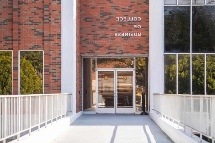 A brick building with the words "College of 业务" in metal letters placed above a door.