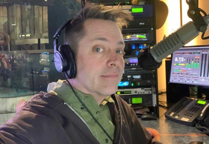 A male in a radio studio looking at the camera.