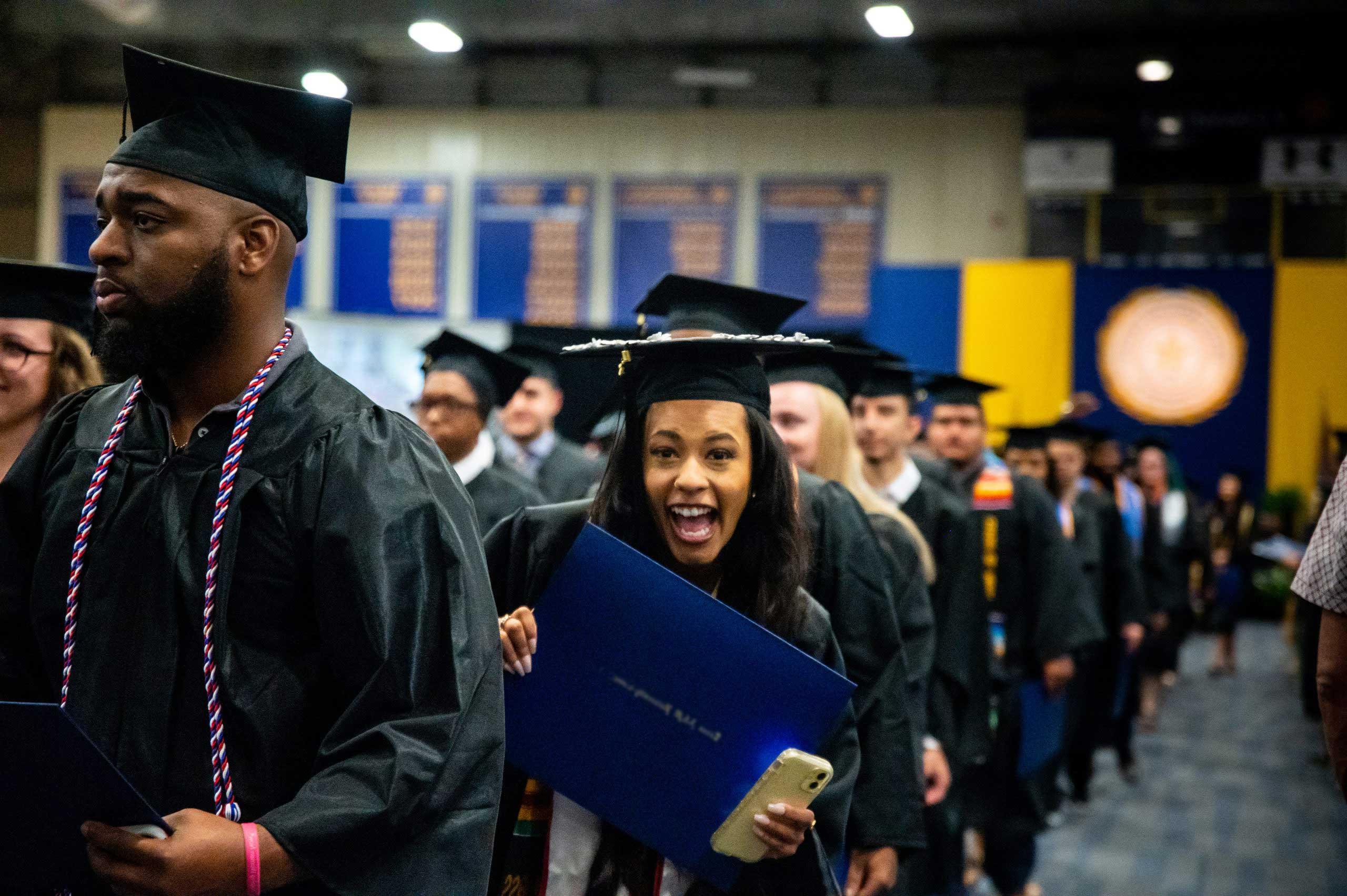 A female student graduating and smiling at the camera man.