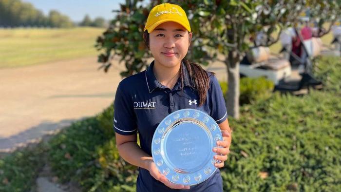 高尔夫球er smiles at camera while holding a silver commemorative plate