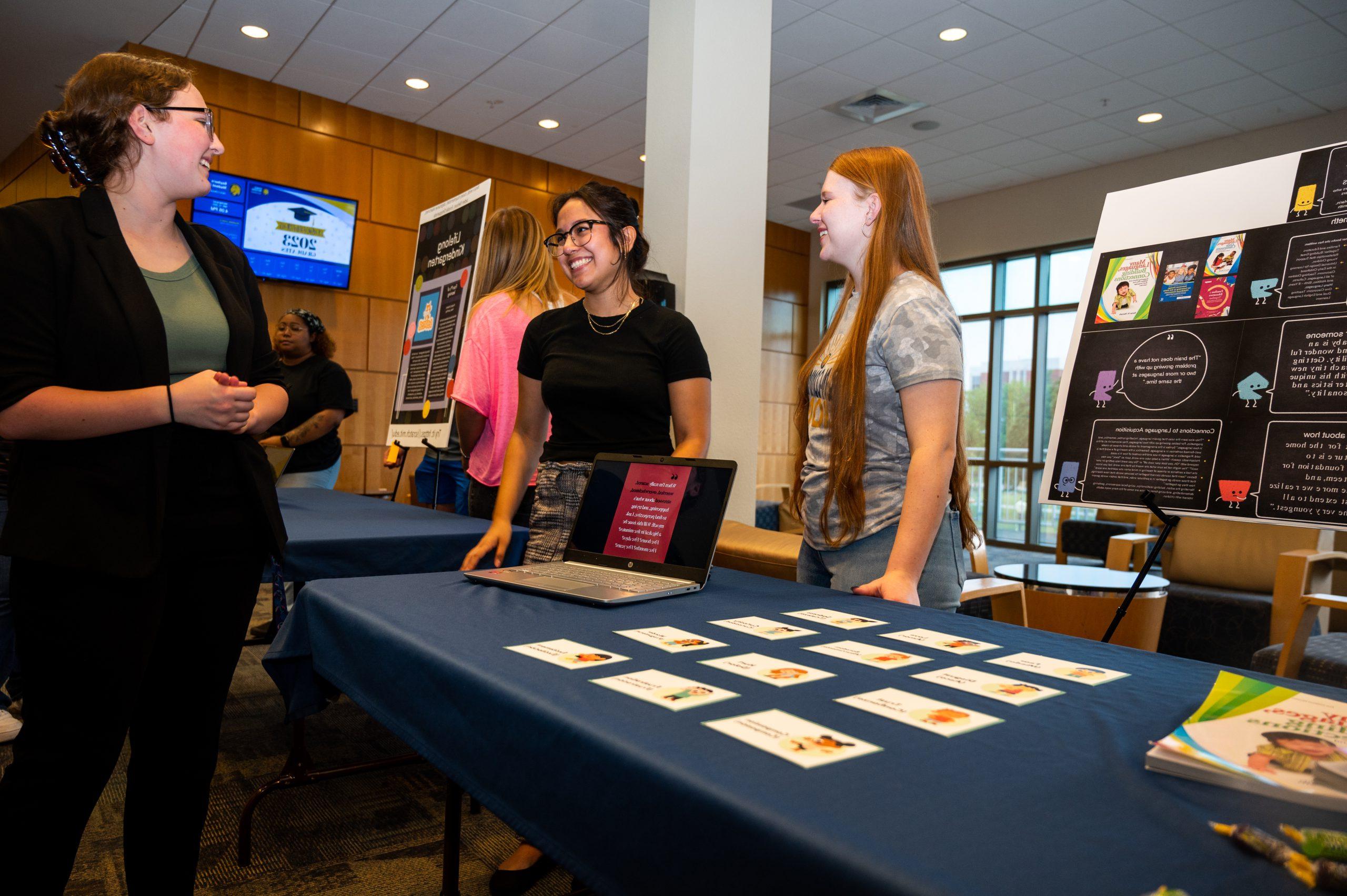 Three female student presenting at a conference.