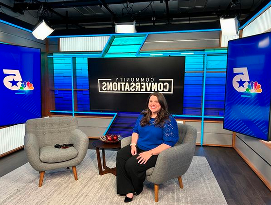 A person sitting in a chair on the set of a television news studio.